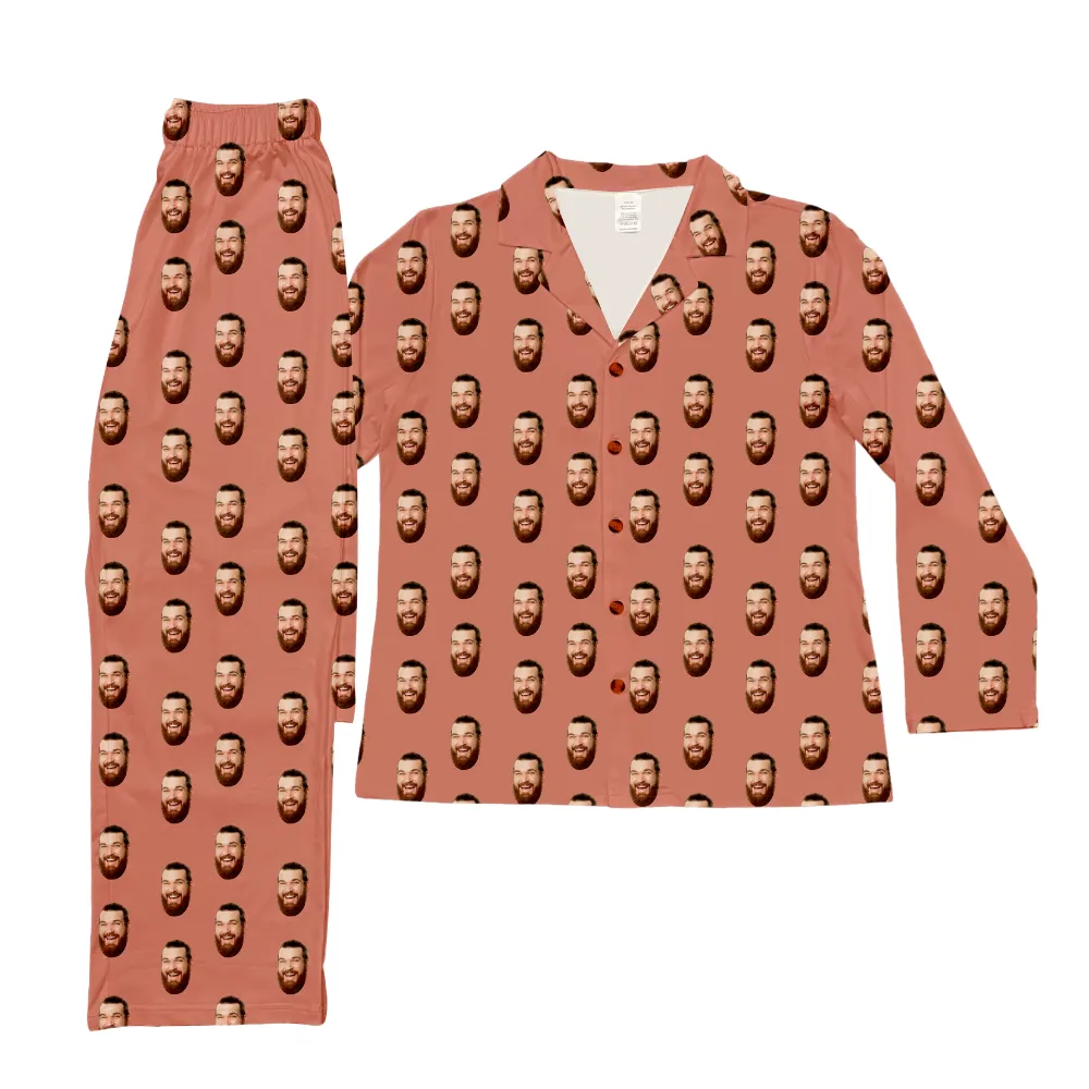 Select to view 'Long-sleeve button-up pajama top paired with matching full-length pants in dusty rose with repeated smiling bearded face print.' image
