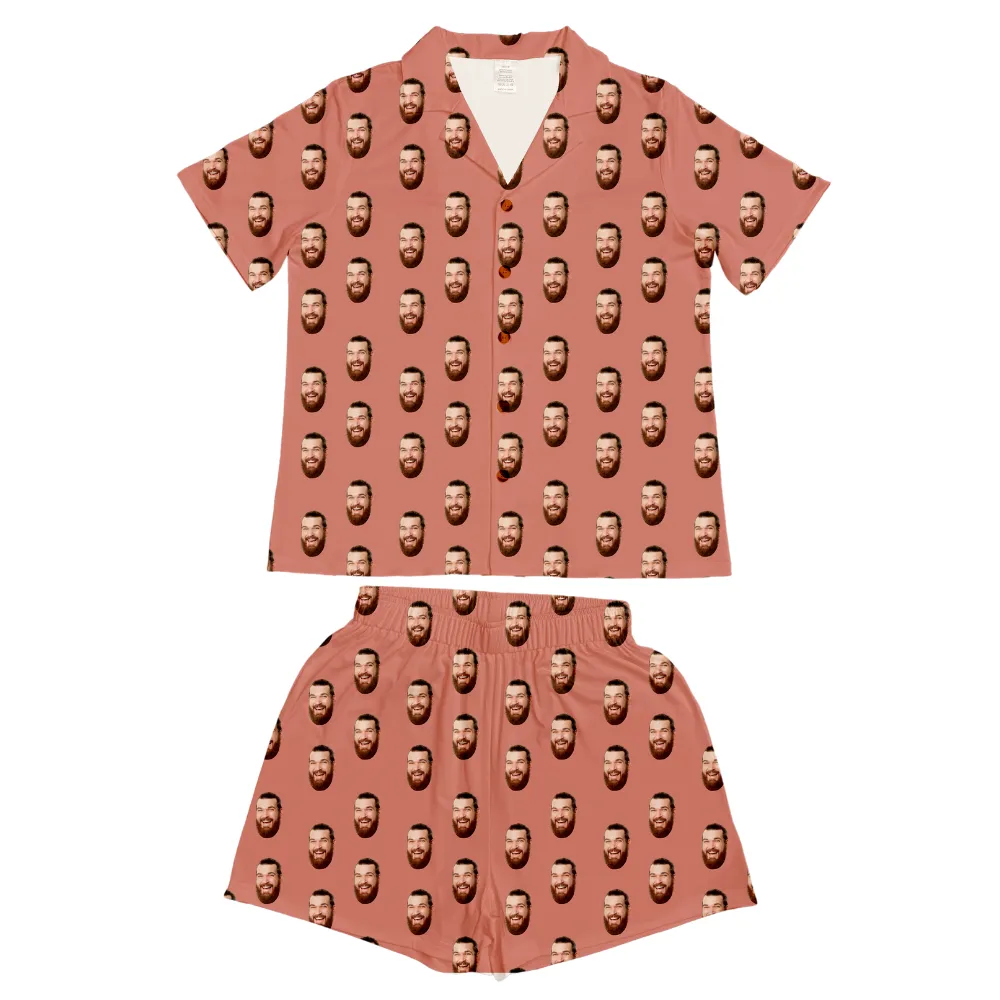 Select to view 'Short-sleeve pajama set in dusty rose featuring a playful all-over pattern of a smiling bearded man's face on soft fabric.' image